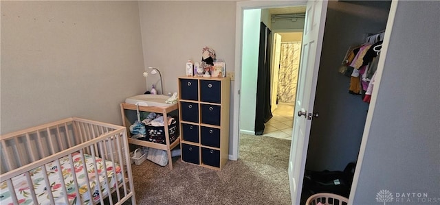 carpeted bedroom featuring a closet and a nursery area