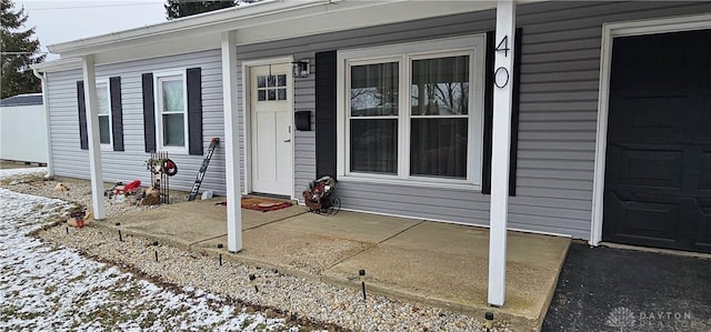 snow covered property entrance with a porch