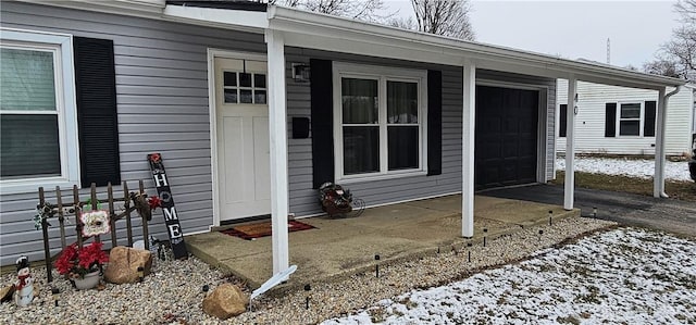 snow covered property entrance featuring a garage