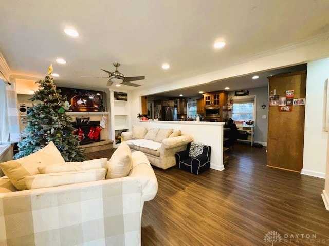 living room with crown molding, ceiling fan, and dark wood-type flooring