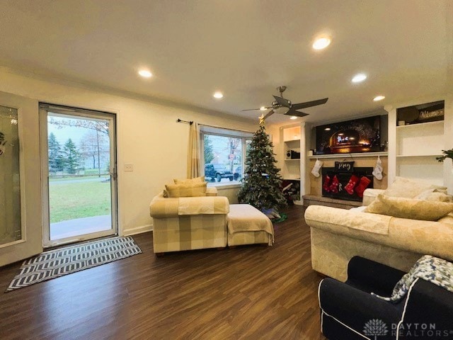 living room featuring a wealth of natural light, built in features, ceiling fan, and dark hardwood / wood-style floors