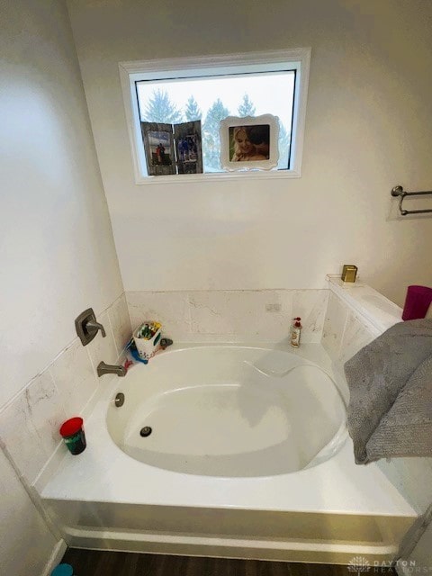 bathroom with a tub to relax in and a healthy amount of sunlight