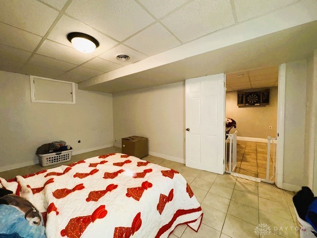 bedroom featuring a paneled ceiling and light tile patterned floors