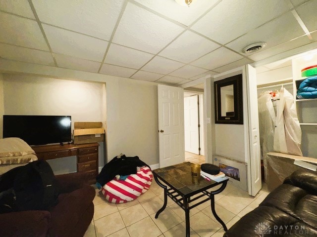 living room with a drop ceiling and light tile patterned flooring