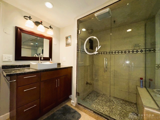 bathroom with tile patterned flooring, vanity, and walk in shower