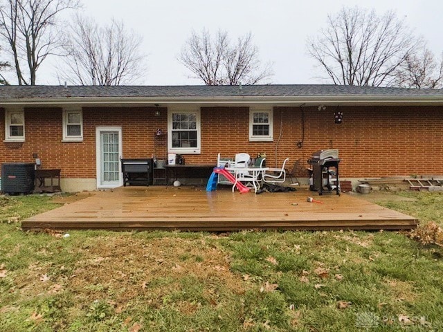 rear view of property with a yard, central air condition unit, and a wooden deck