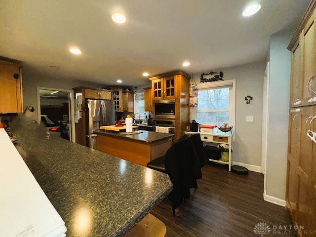 kitchen with a center island, a kitchen breakfast bar, sink, dark hardwood / wood-style flooring, and stainless steel appliances