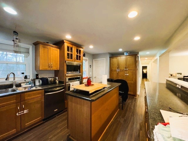 kitchen with sink, dark hardwood / wood-style floors, dark stone countertops, appliances with stainless steel finishes, and a kitchen island