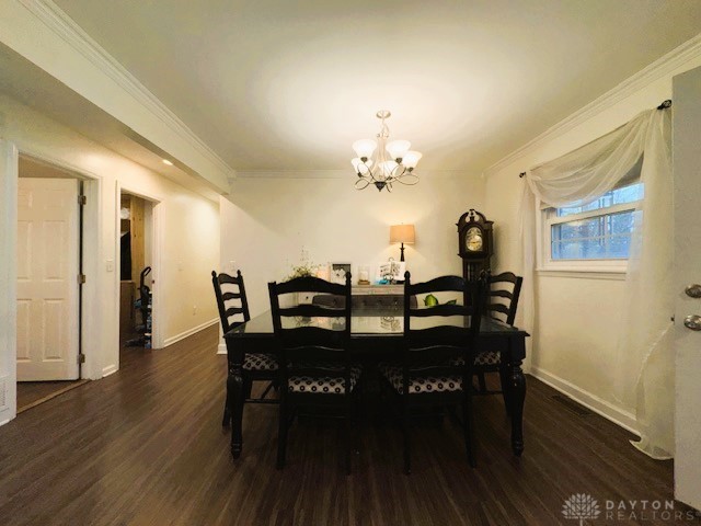 dining space featuring dark hardwood / wood-style flooring, ornamental molding, and an inviting chandelier