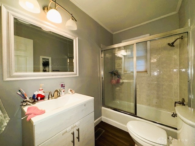 full bathroom featuring enclosed tub / shower combo, crown molding, wood-type flooring, toilet, and vanity