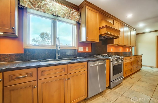 kitchen with appliances with stainless steel finishes, custom exhaust hood, crown molding, sink, and light tile patterned floors