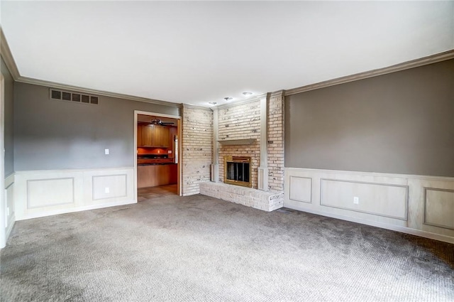 unfurnished living room with carpet flooring, a brick fireplace, and crown molding