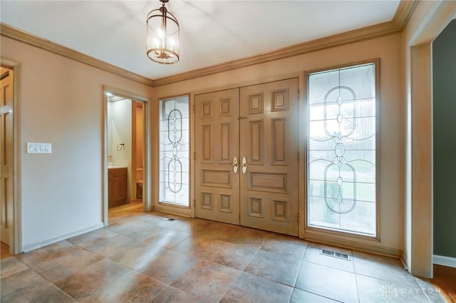 foyer with ornamental molding, a wealth of natural light, and a chandelier