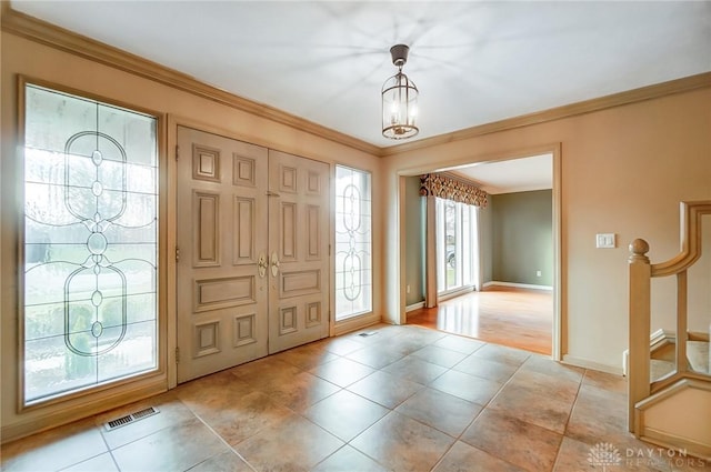 foyer featuring a chandelier and crown molding