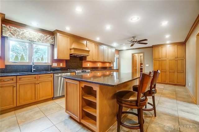 kitchen featuring appliances with stainless steel finishes, custom range hood, ceiling fan, sink, and a kitchen island