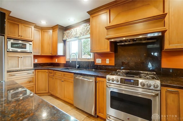 kitchen with sink, dark stone countertops, light tile patterned floors, custom range hood, and appliances with stainless steel finishes