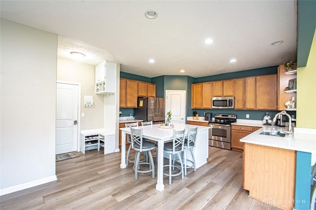 kitchen featuring a breakfast bar, stainless steel appliances, sink, light hardwood / wood-style flooring, and a kitchen island