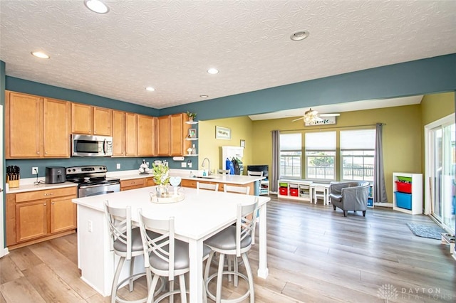 kitchen with a kitchen breakfast bar, a kitchen island with sink, stainless steel appliances, and a textured ceiling