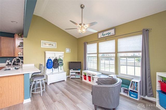 playroom with ceiling fan, lofted ceiling, sink, and light hardwood / wood-style flooring