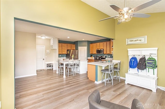 living room with ceiling fan, light wood-type flooring, and sink