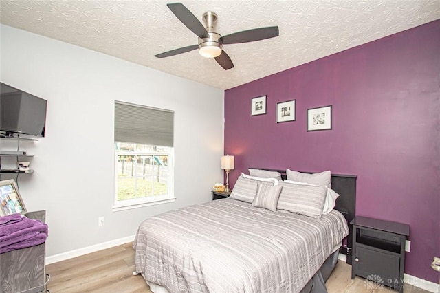 bedroom with a textured ceiling, light hardwood / wood-style flooring, and ceiling fan