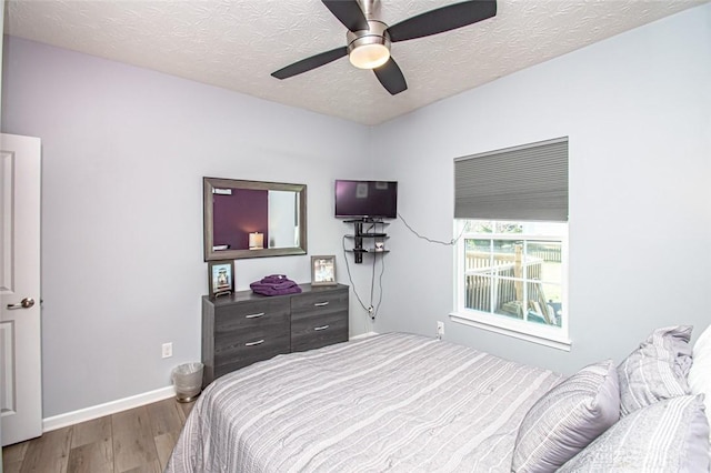 bedroom featuring ceiling fan, wood-type flooring, and a textured ceiling