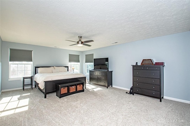 carpeted bedroom featuring ceiling fan and a textured ceiling