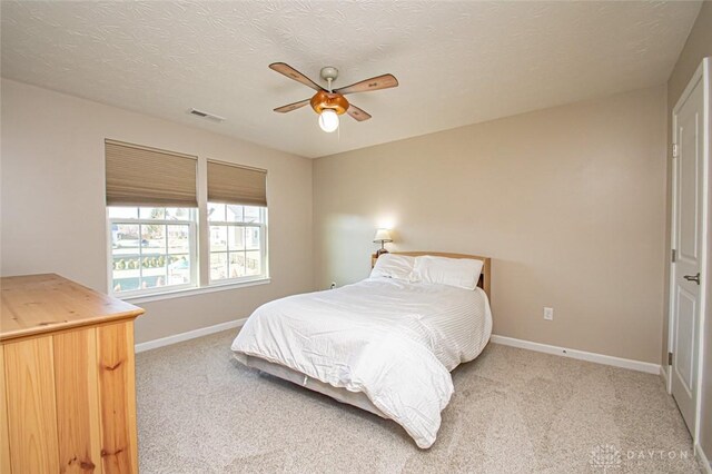 carpeted bedroom with ceiling fan and a textured ceiling