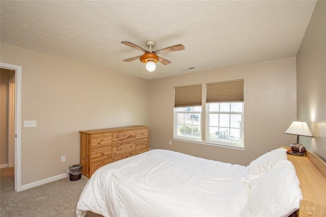 carpeted bedroom featuring ceiling fan and a textured ceiling