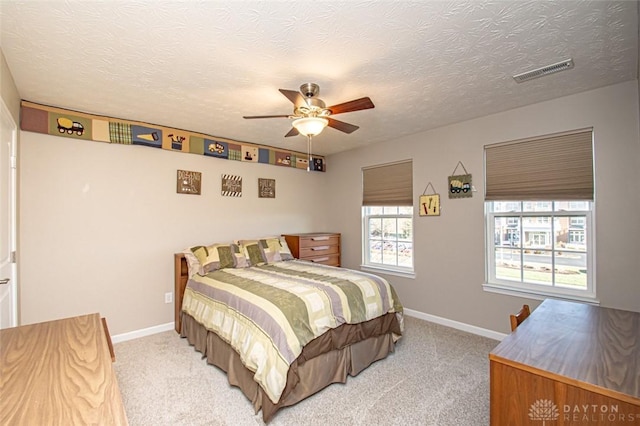 carpeted bedroom with ceiling fan and a textured ceiling