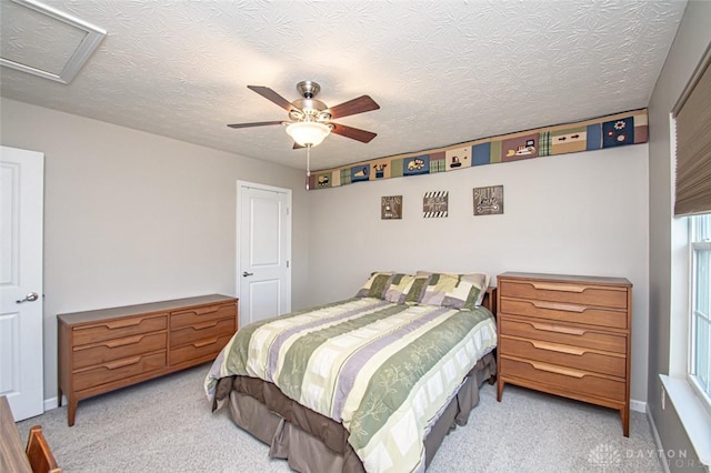 bedroom with ceiling fan, light colored carpet, and a textured ceiling