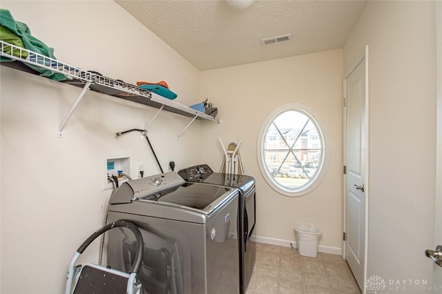 laundry area featuring a textured ceiling and washing machine and clothes dryer