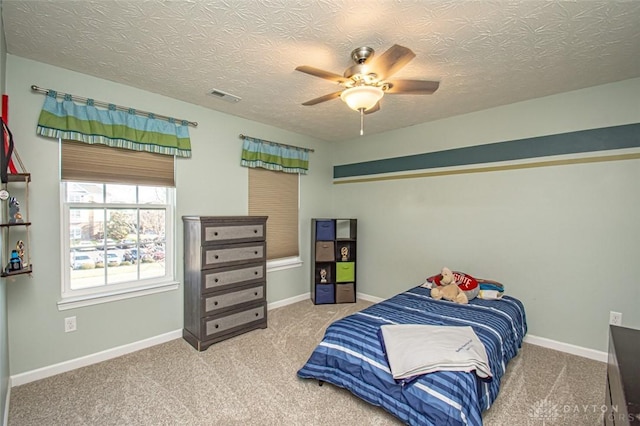 carpeted bedroom featuring ceiling fan and a textured ceiling