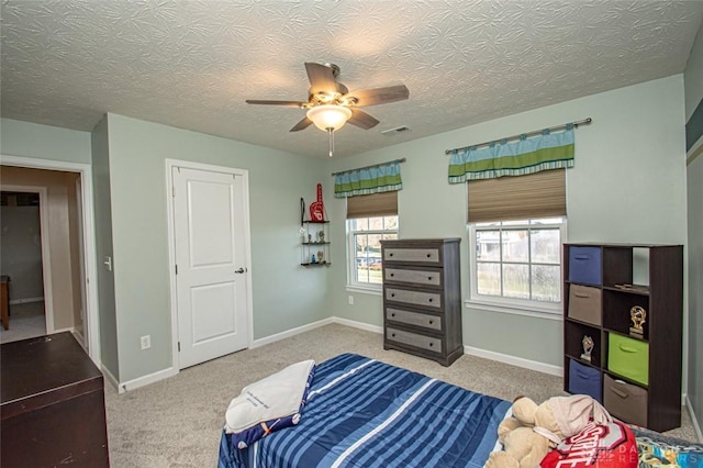 bedroom with a textured ceiling, carpet floors, and ceiling fan