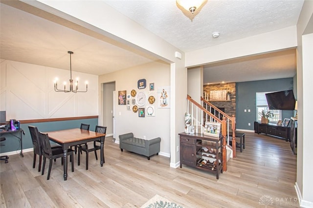 dining room featuring a textured ceiling, light hardwood / wood-style floors, and an inviting chandelier