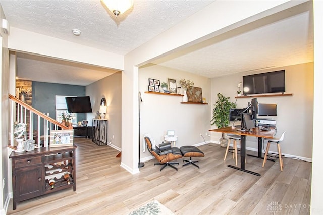 home office featuring light hardwood / wood-style floors and a textured ceiling