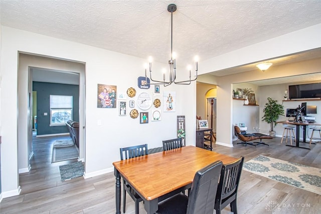 dining area featuring an inviting chandelier, a textured ceiling, and hardwood / wood-style flooring