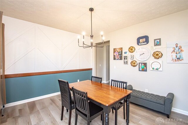 dining space with hardwood / wood-style flooring, a textured ceiling, and a notable chandelier