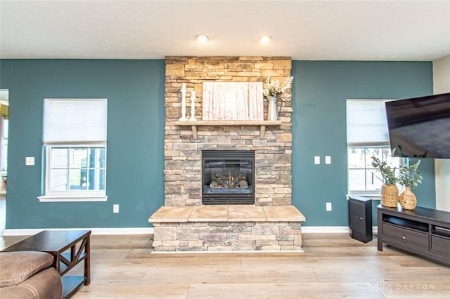 living room with light hardwood / wood-style floors and a stone fireplace