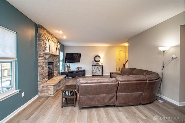 living room with light hardwood / wood-style flooring and a stone fireplace