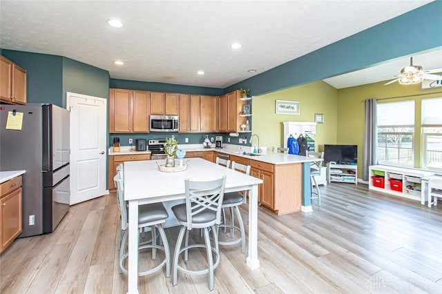 kitchen featuring a breakfast bar, a center island, stainless steel appliances, and light hardwood / wood-style flooring