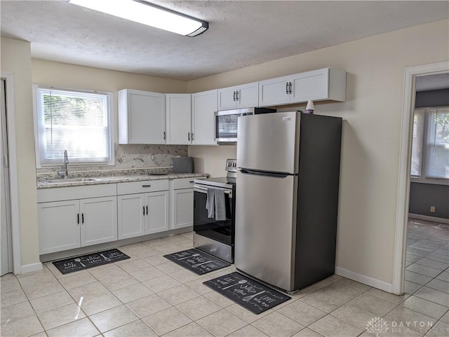 kitchen featuring appliances with stainless steel finishes, a textured ceiling, sink, white cabinetry, and light tile patterned flooring