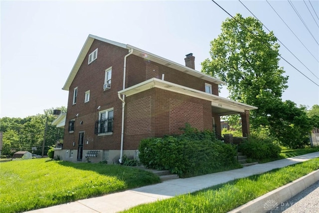 view of side of home with a yard, a chimney, and brick siding