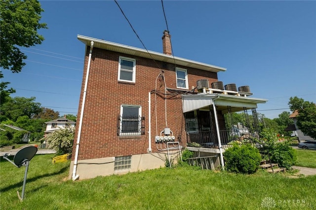 rear view of house with covered porch, a yard, and central air condition unit