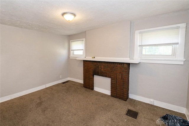 carpeted spare room featuring a fireplace and a textured ceiling