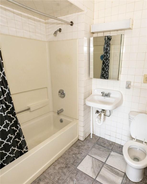 full bathroom featuring sink, toilet, tile walls, and shower / tub combo