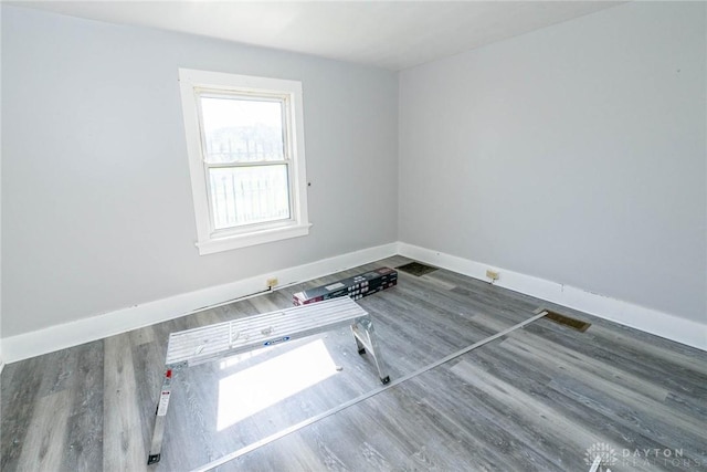 unfurnished room with wood finished floors, visible vents, and baseboards