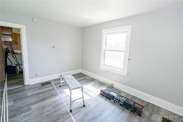 unfurnished room with baseboards and wood finished floors