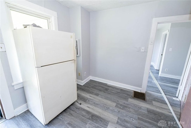 kitchen with baseboards, visible vents, wood finished floors, and freestanding refrigerator