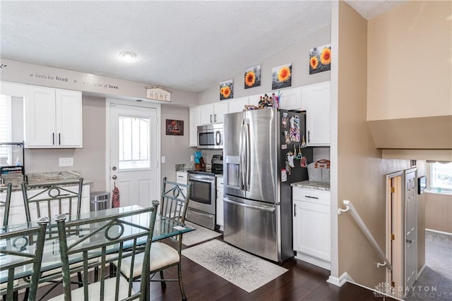 kitchen featuring light stone countertops, white cabinets, dark wood-type flooring, and appliances with stainless steel finishes